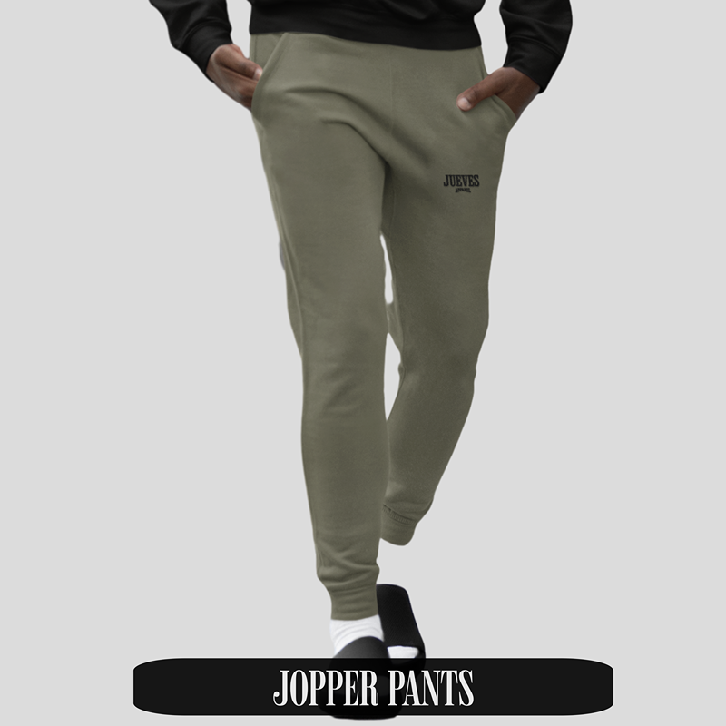 Mann trägt khakifarbene Jogger Pants von Jueves Apparel mit Logo auf dem Bein – stylische Streetwear-Hose aus hochwertiger Baumwolle für urbanen Look.