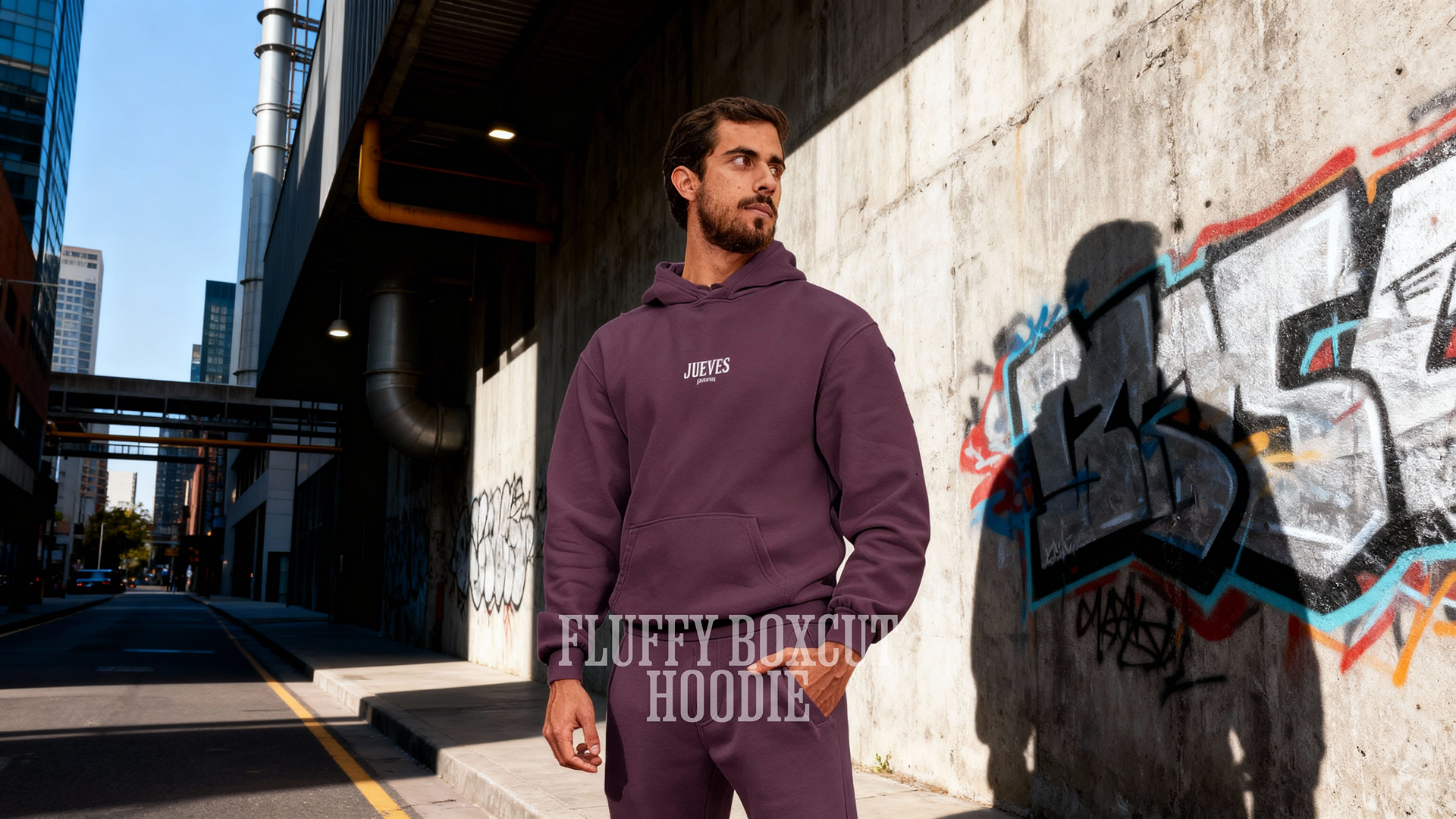 Mann trägt einen Fluffy Boxcut Hoodie "Basic White" in Plum Purple aus 70 % Baumwolle und 30 % Polyester – moderner Streetwear- und Urban-Style von Jueves Apparel.